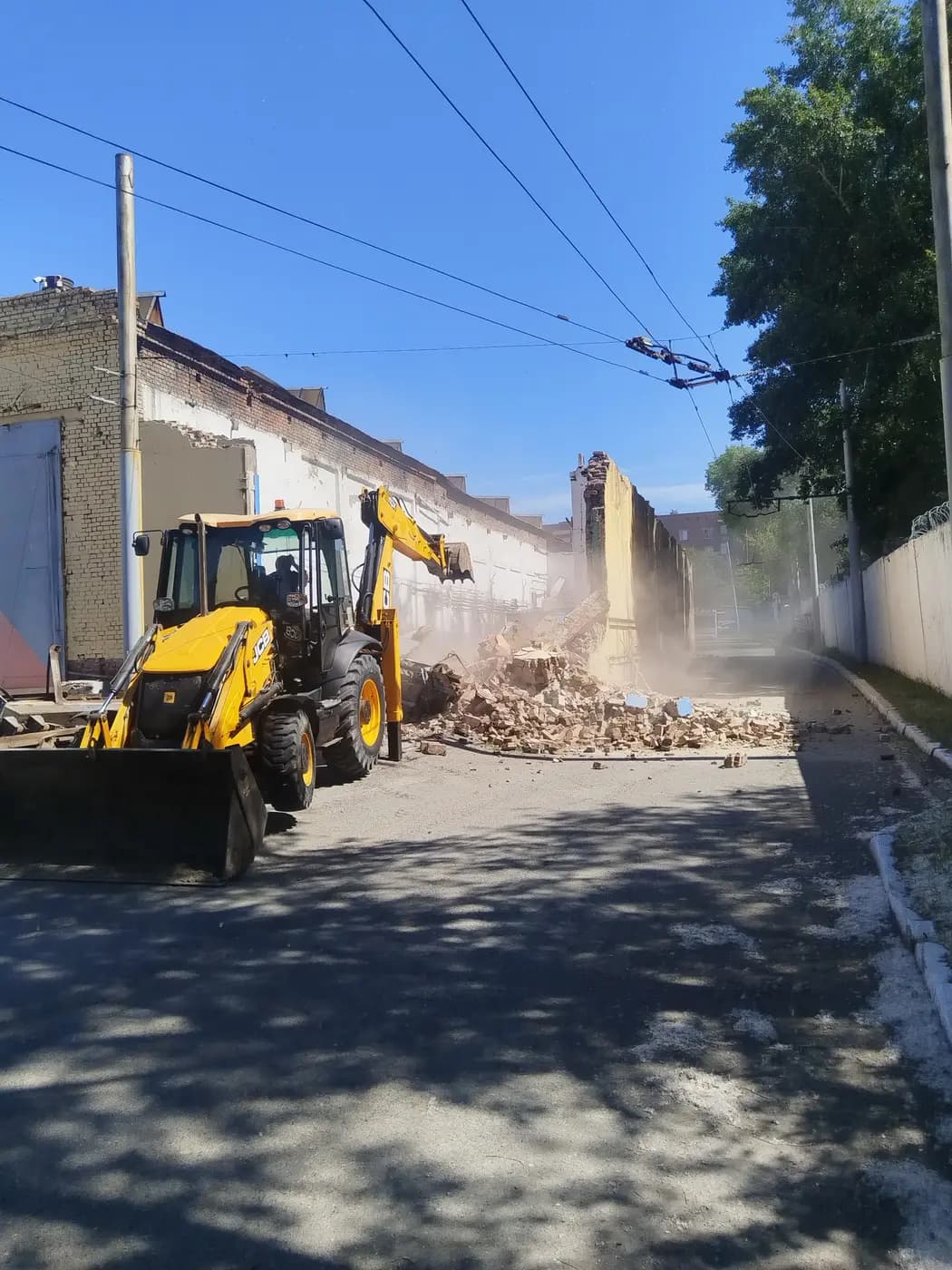 Экскаватор в узком проходе между стенами при демонтаже